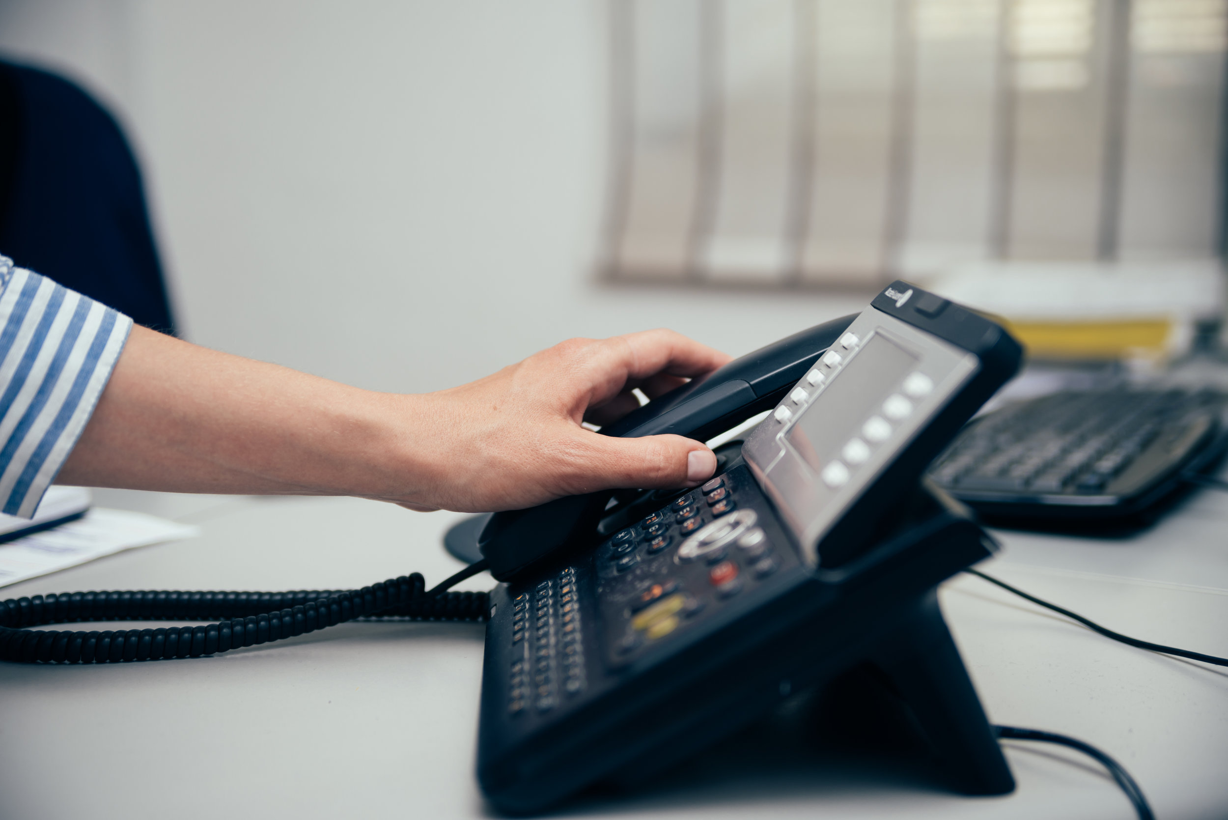 A receptionist picking up the telephone to answer patients’ calls
