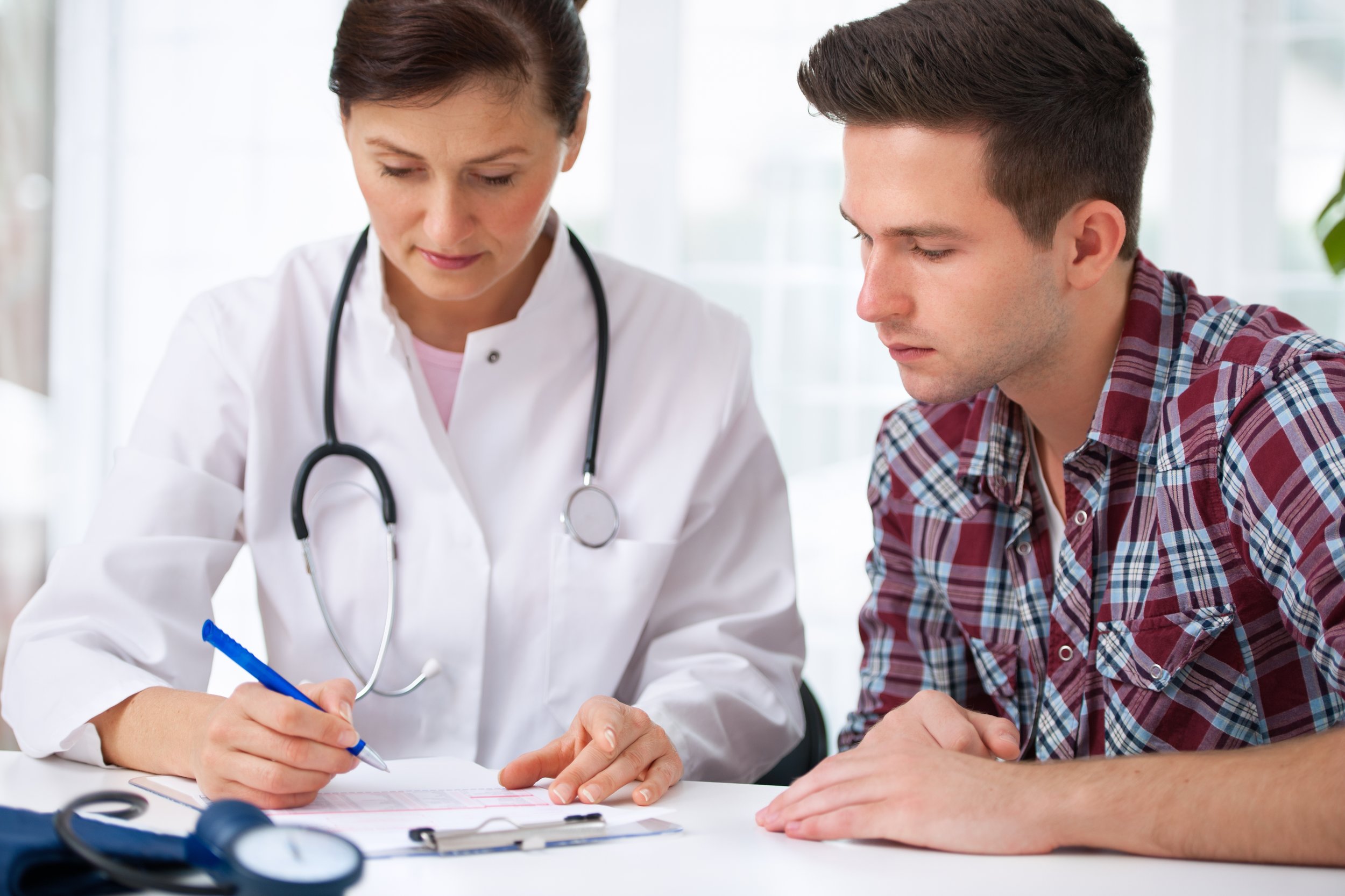 Medical doctor going over insurance and medical bills with male patient