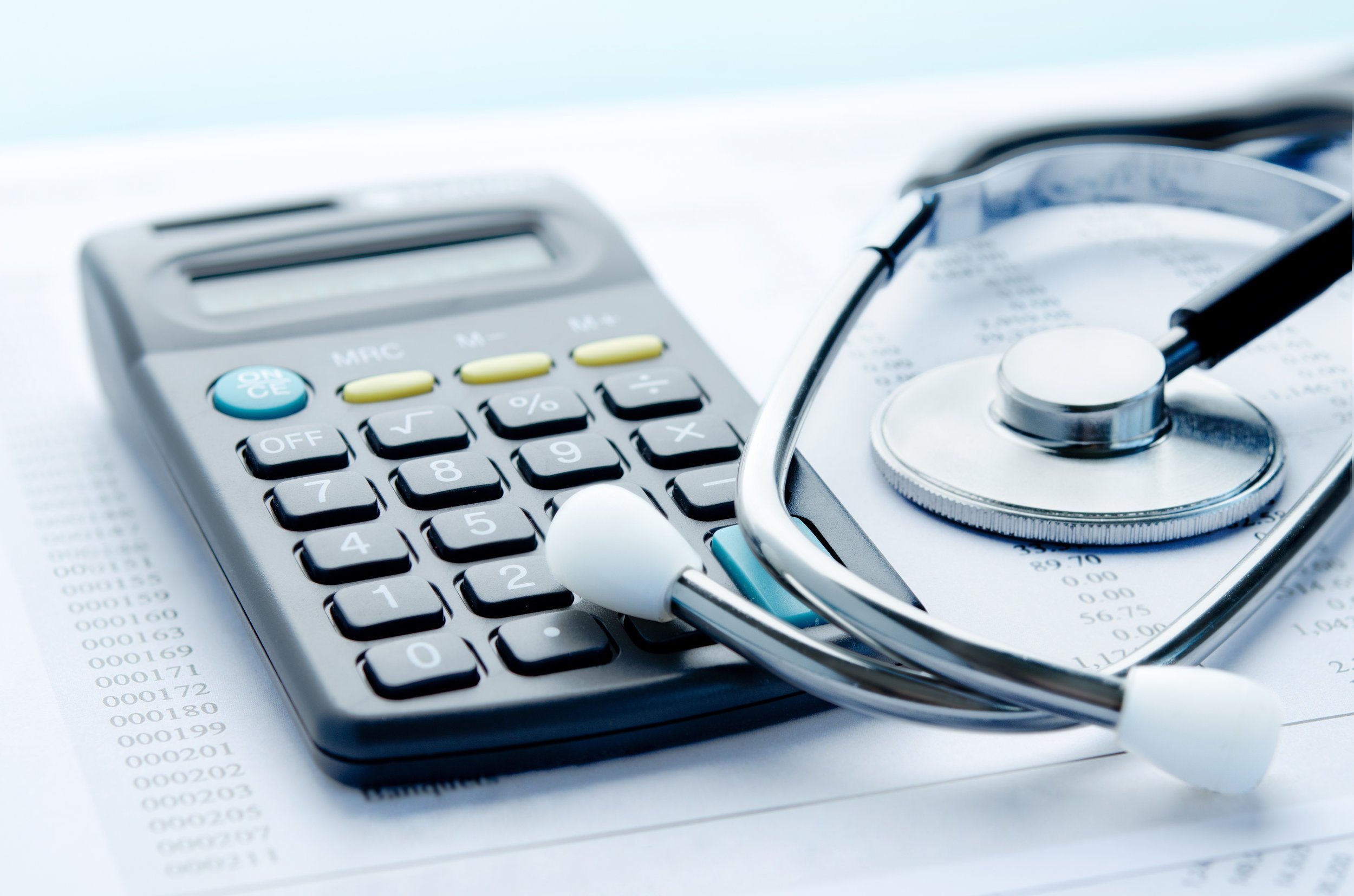 Calculator and stethoscope overlayed on sheets of paper filled with numbers, symbolizing expensive healthcare costs