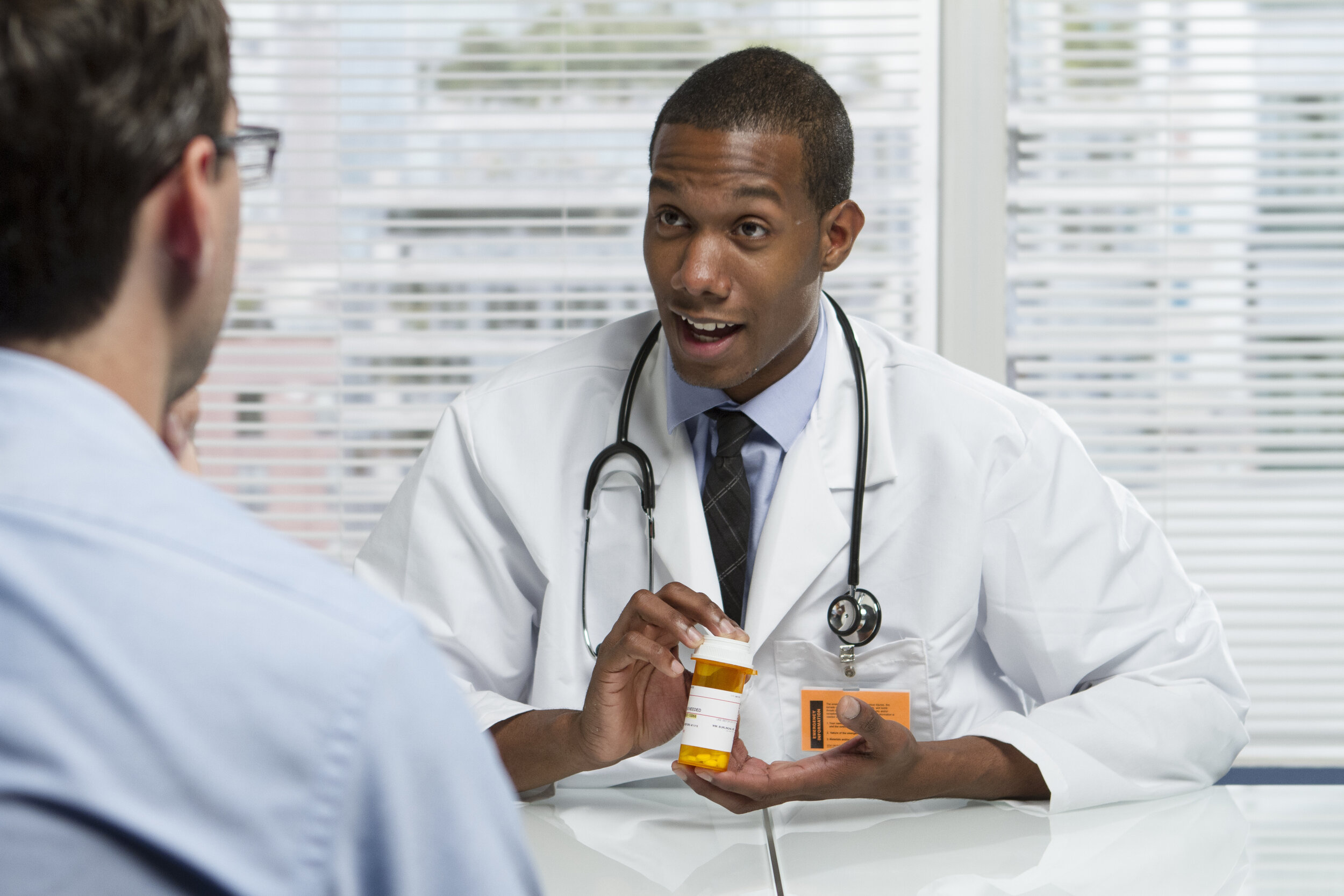 Male doctor prescribing medication to middle-aged male patient in the doctor’s office