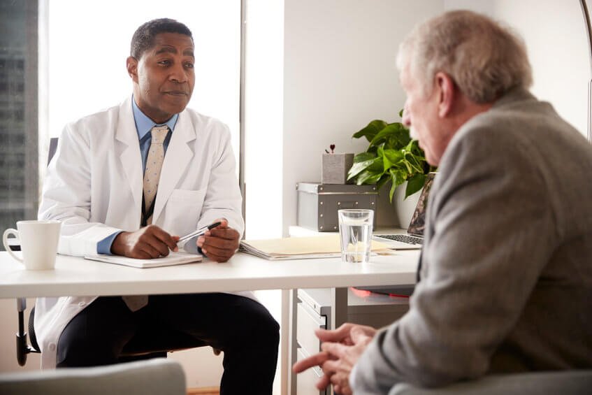 A male surgeon counseling a senior male patient on which screening service to move forward with at a direct primary care clinic