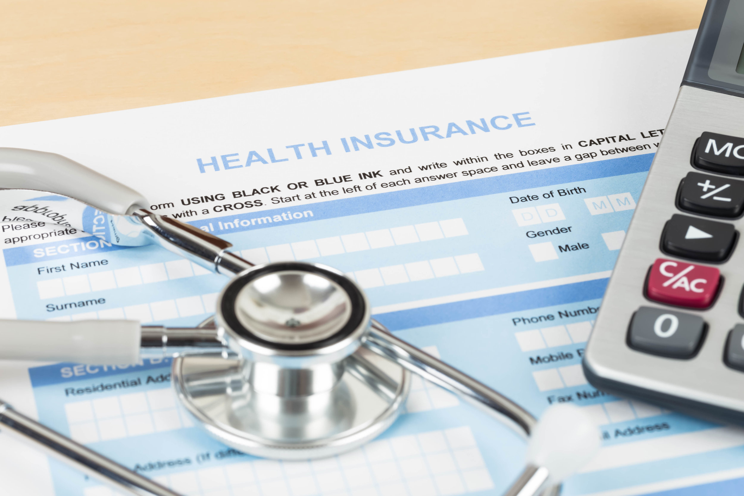Flat lay of health insurance application form with calculator and stethoscope