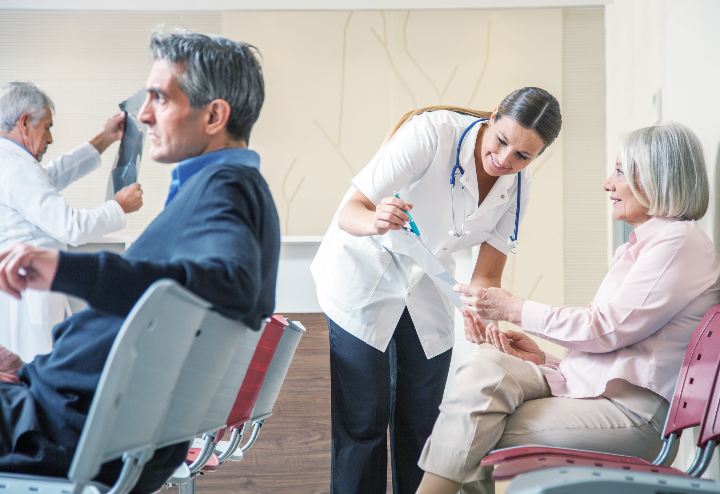 Doctors making referrals and discussing test results with patients in a hospital clinic waiting area