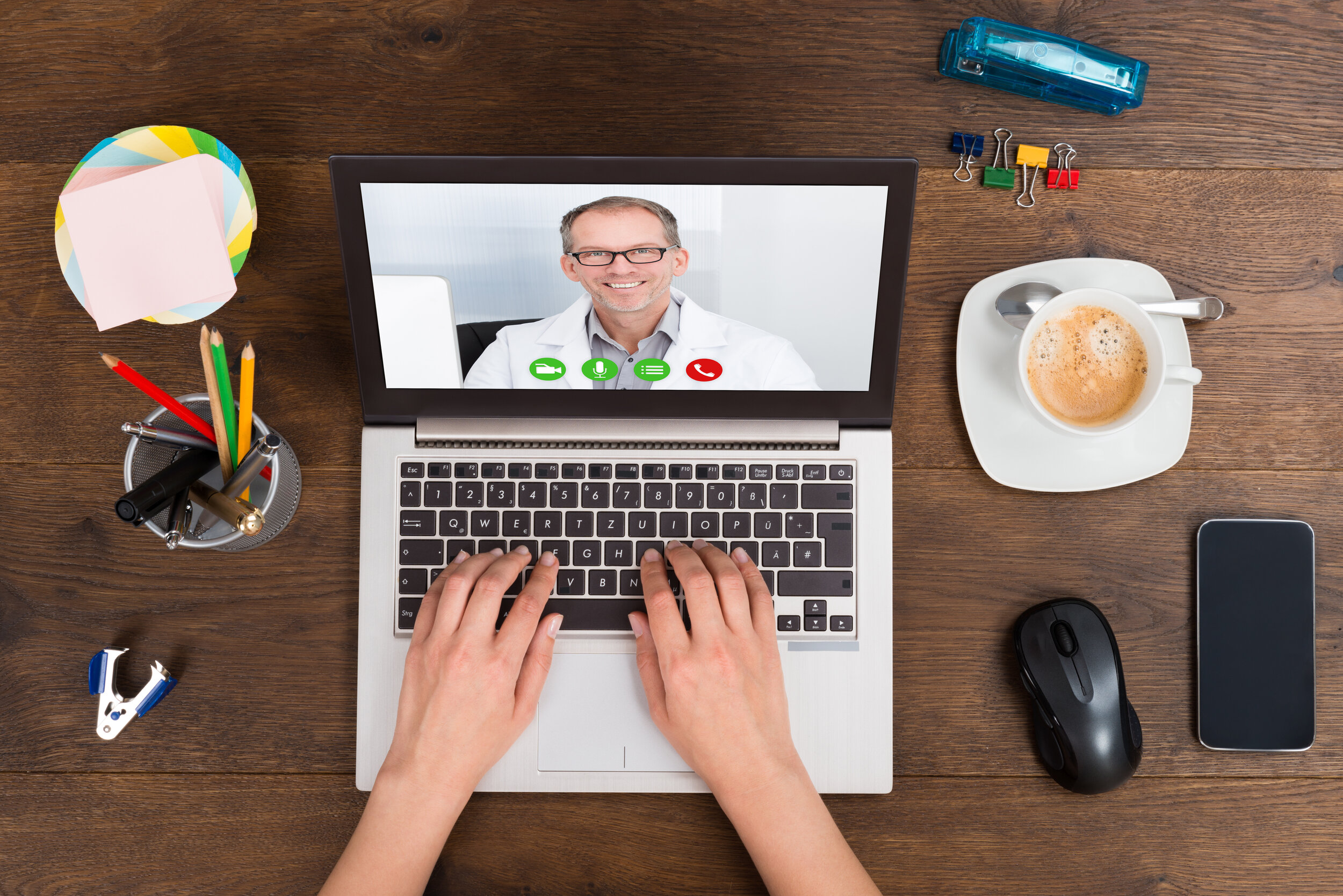 Closeup of a patient’s hands on laptop while consulting with their male doctor via telemedicine.