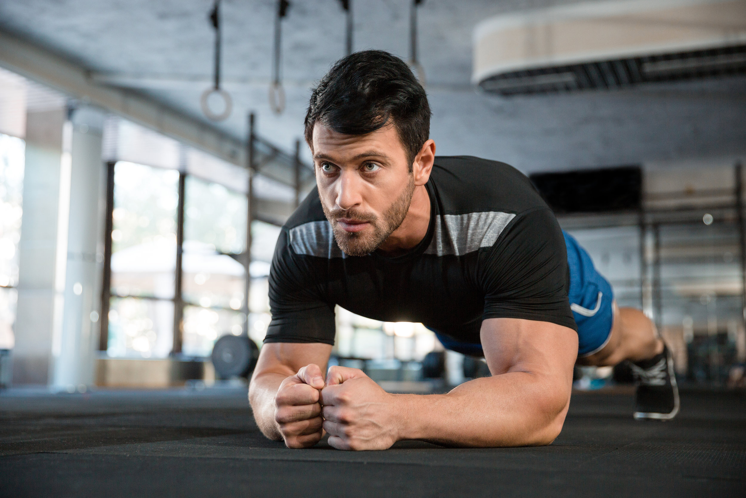 Male athlete wearing blue shorts and black t-shirt improving overall body composition through physical exercises
