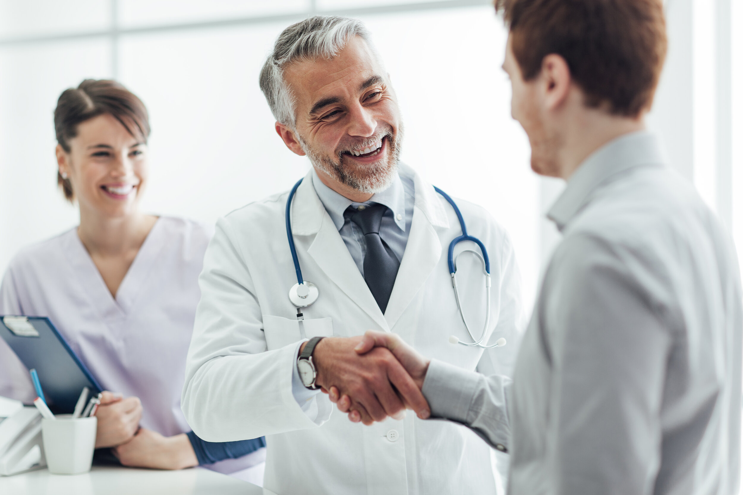 Friendly middle-aged family doctor interacting with a patient by shaking his hand