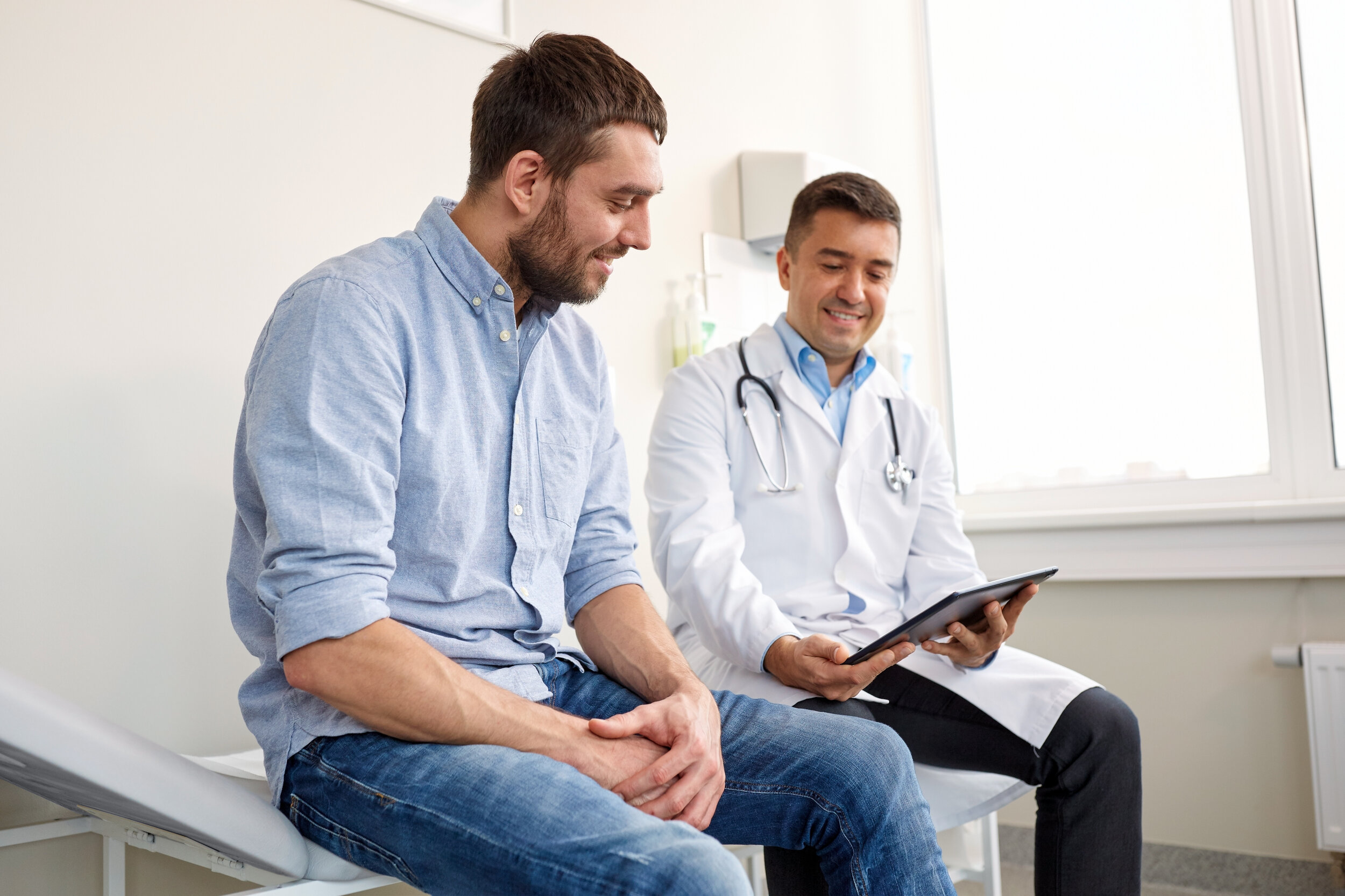 Middle-aged male visiting with his direct primary care doctor, at a routine check-up