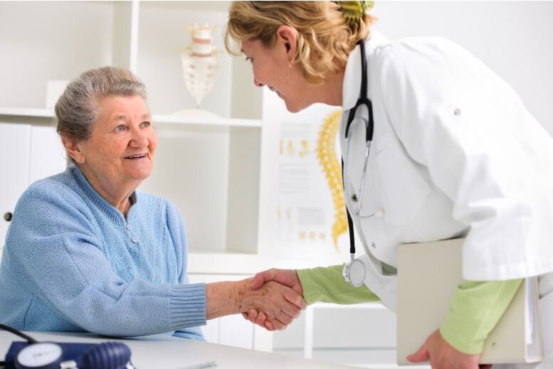 Female physician shaking hands with an elderly female patient at an introductory meeting