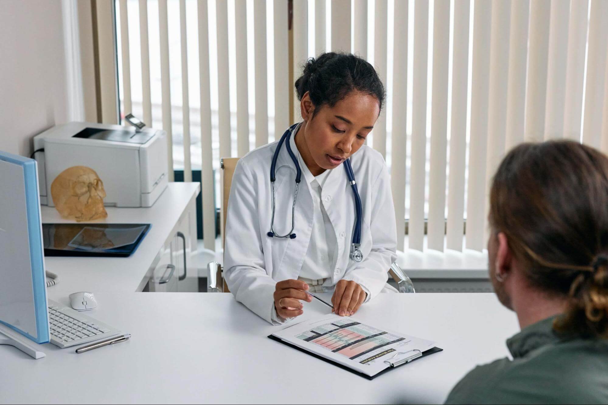 A female primary care physician reviewing lab results with a male patient in a doctor’s office