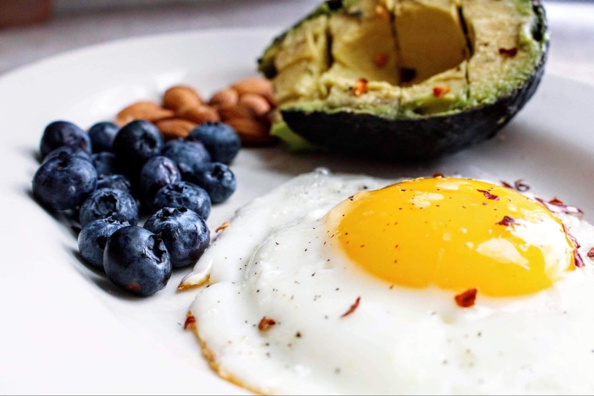 A keto-friendly breakfast of eggs, avocado, blueberries, and almonds