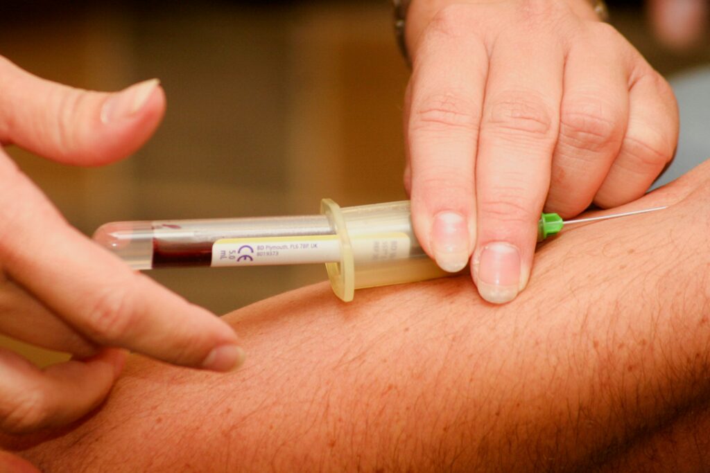 A medical professional drawing blood from a patient’s arm using a needle